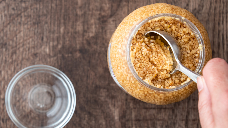 A person scooping out minced garlic from a jar.