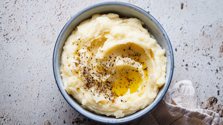 an overhead shot of a bowl of mashed potatoes with melted butter and pepper