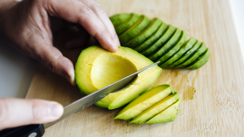 Hands slicing an avocado