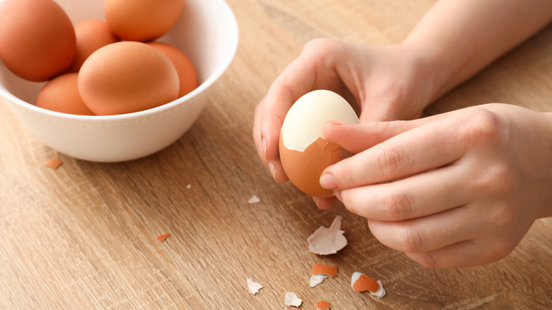 A bowl of eggs, one being peeled