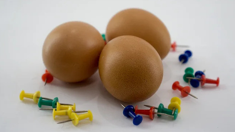 Three hard boiled eggs with push pins