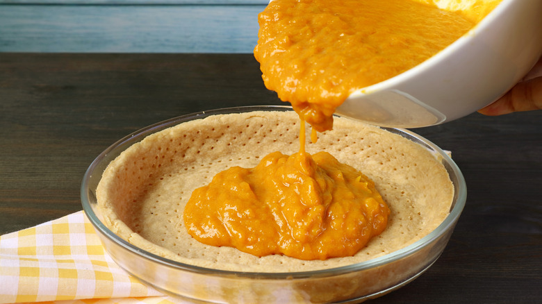 Pouring pumpkin pie mixture into crust