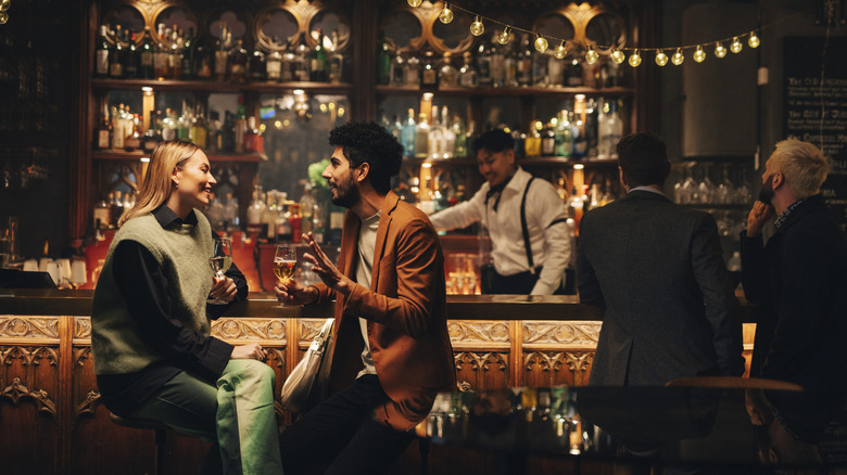 Man and woman talking and laughing with drinks at a fancy bar