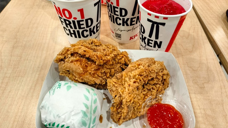 A KFC meal of chicken, a sandwich, and drinks