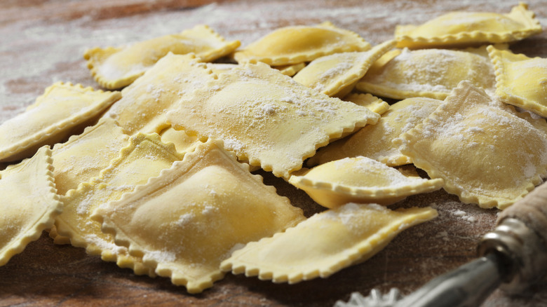 A pile of fresh ravioli sitting on a wooden table.