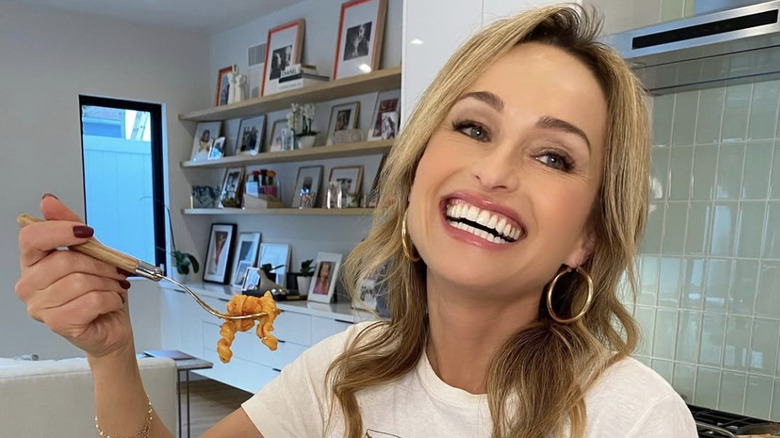 Giada De Laurentiis holding pasta on a fork and smiling