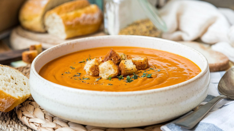 A bowl of tomato soup with chunks of bread