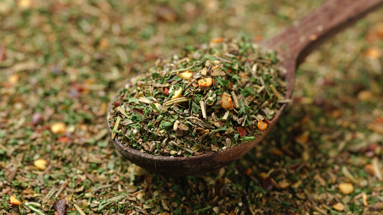 Dried mixed herbs on a wooden spoon