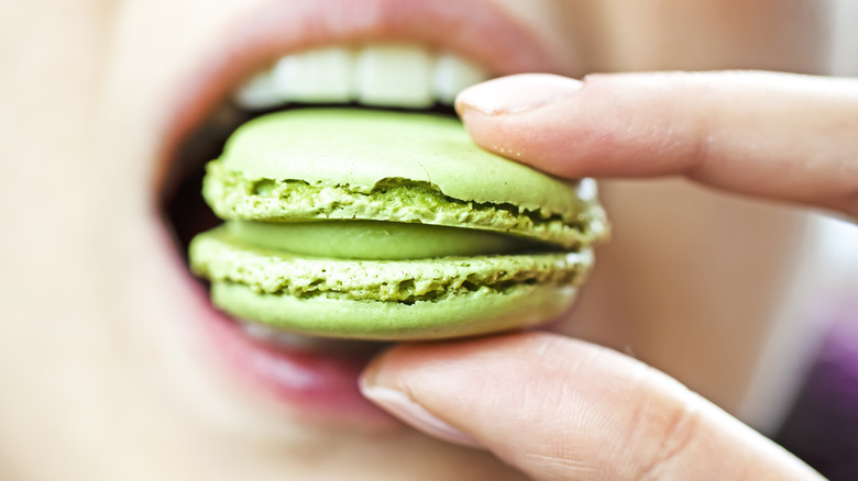 Closeup of a person biting into green macaron