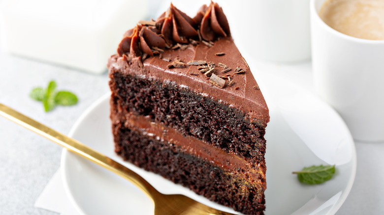 A slice of rich chocolate layer cake on a plate with a fork