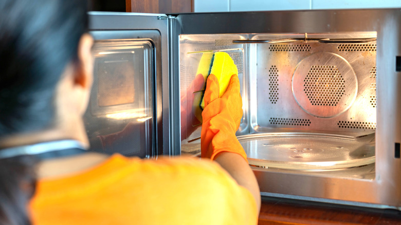 Person cleaning a microwave's interior