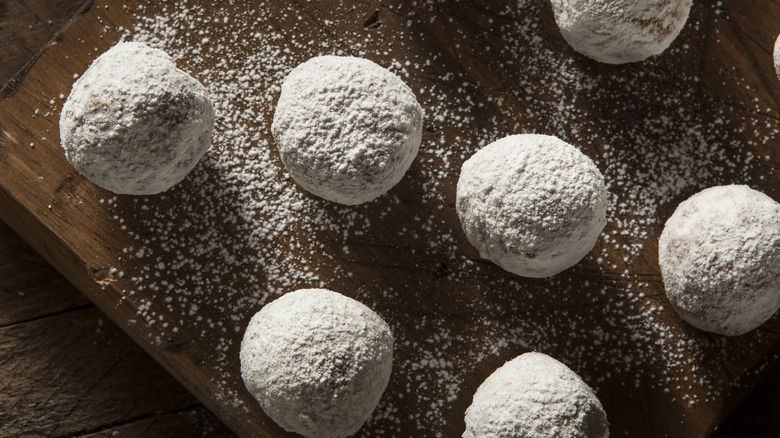 homemade powdered sugar donut holes on a wooden cutting board