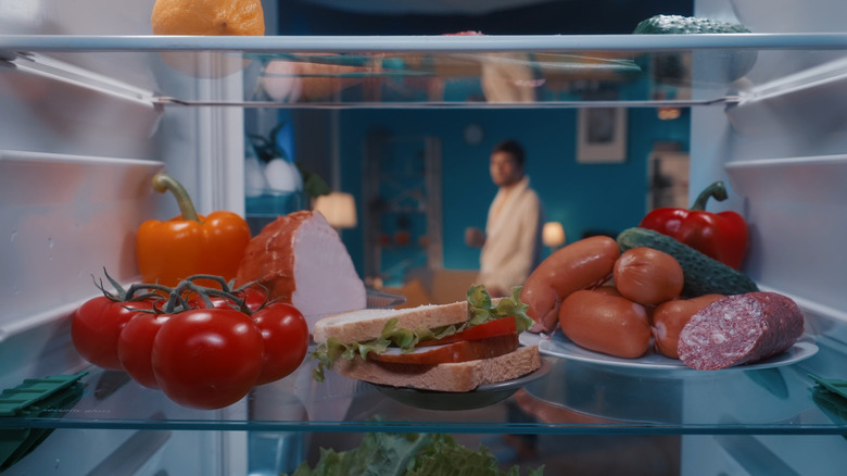 man looking at ingredients in refrigerator