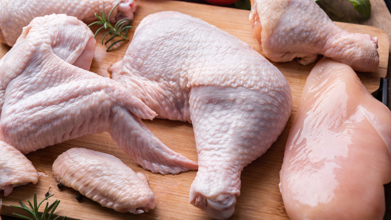 uncooked chicken parts on wood platter