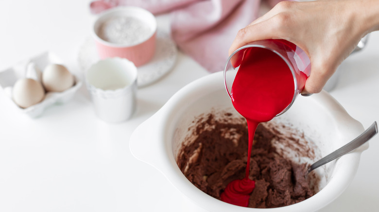 pouring red food dye into a chocolate batter