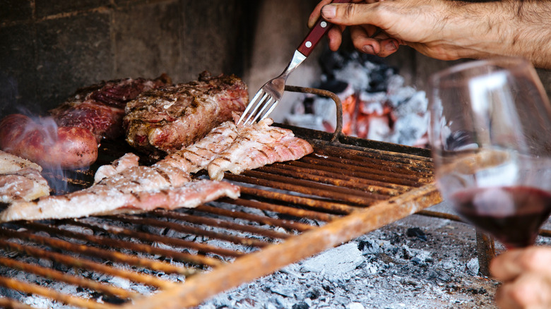 Cooking meat on a grill with a glass of wine