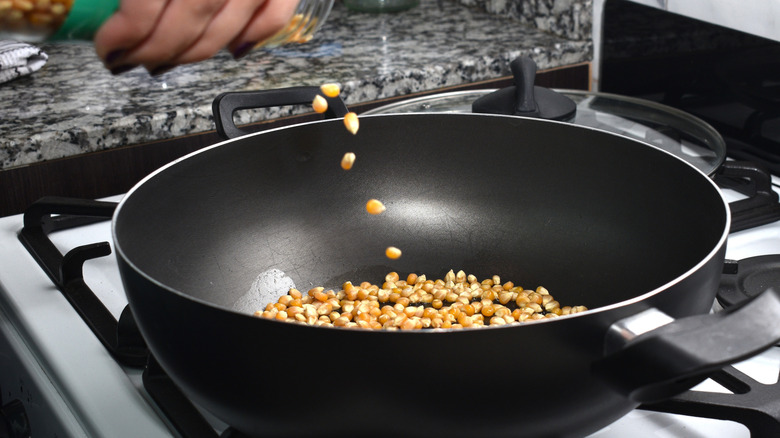 Cooking popcorn kernels in a black pan on the stove