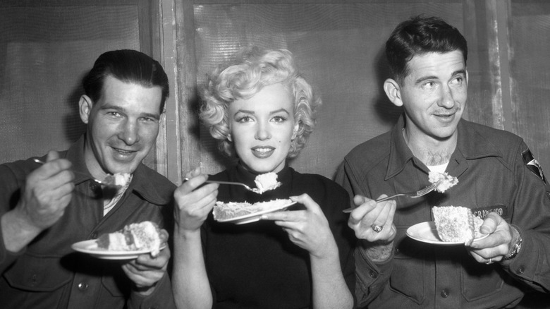 Marilyn Monroe eating a meal with soldiers in South Korea.