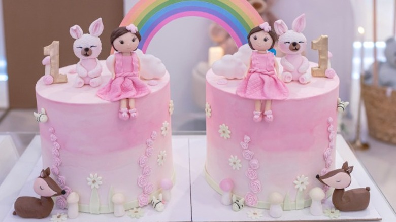 Two birthday cakes, with figures made of fondant sitting atop.