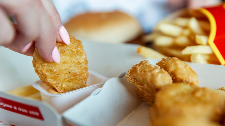 A woman eats Chicken Nuggets at McDonalds. Close-up.