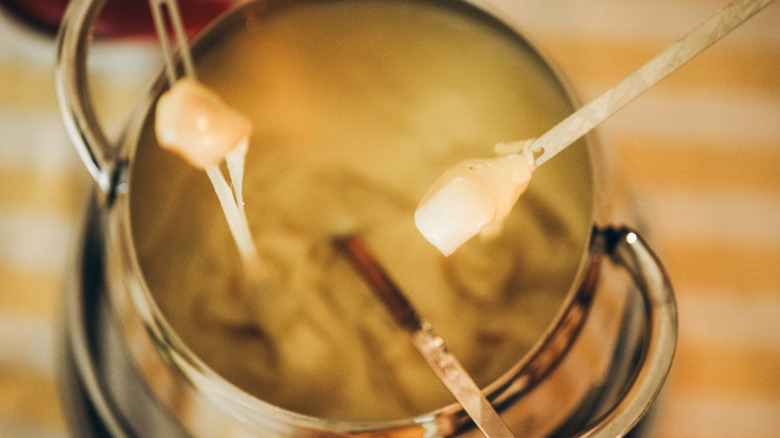 Group of people dipping skewers into a pot of fondue