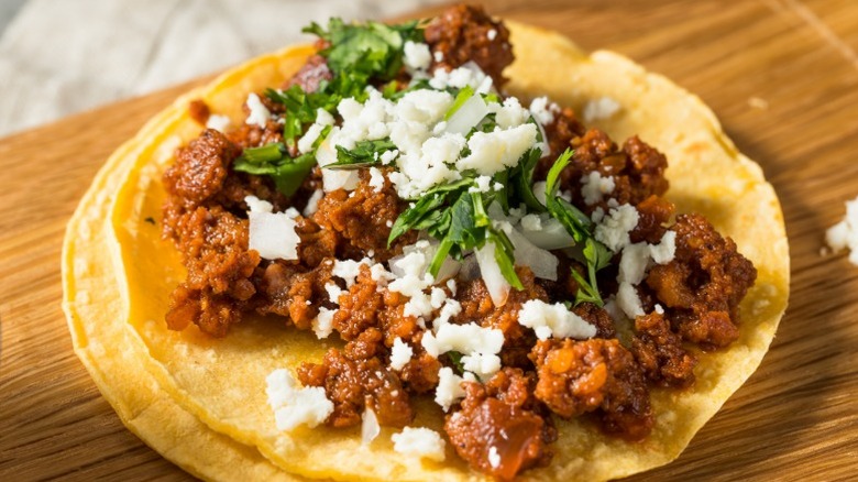 A taco filled with Mexican chorizo and sprinkled with cheese and herbs