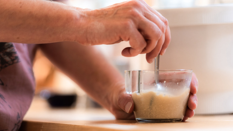 person stirring yeast in glass