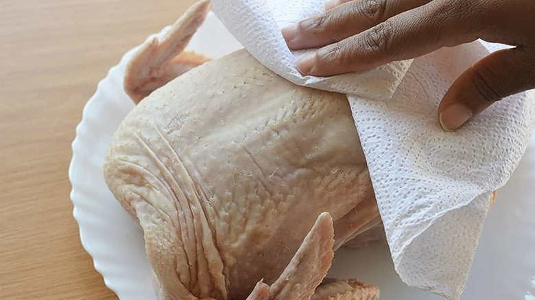 Pat drying raw chicken with a paper towel