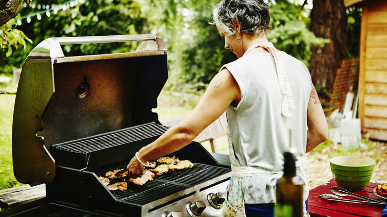 Woman grilling chicken in a barbecue