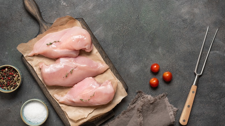 Raw chicken breasts on a wooden board