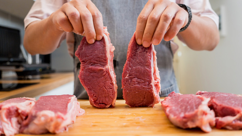 Man holding raw steaks