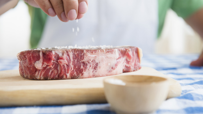 Person seasoning a steak