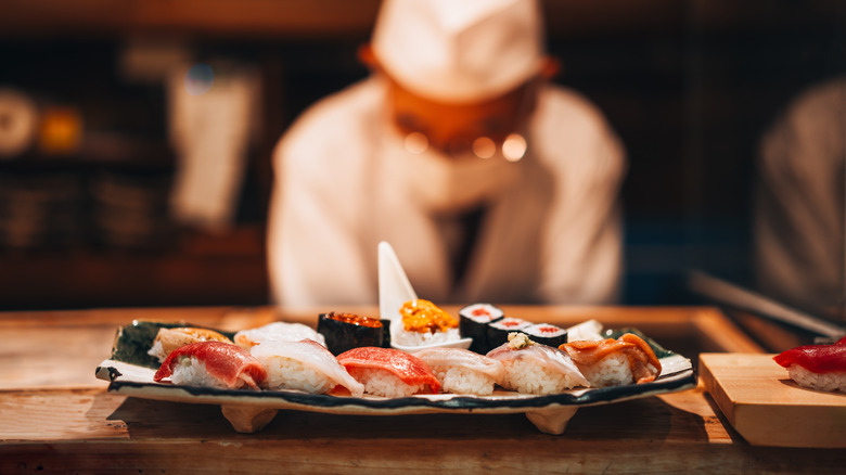 Sushi chef working behind a plate of sushi on counter