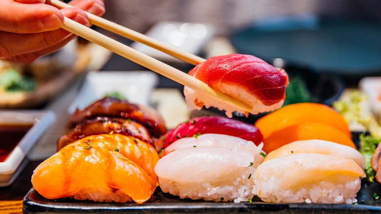 Hand picking up a piece of nigiri with chopsticks