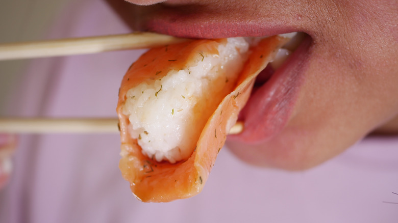 Close up of woman taking a bite of nigiri