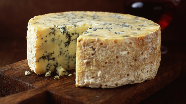 Wheel of crumbly blue cheese with a slice missing