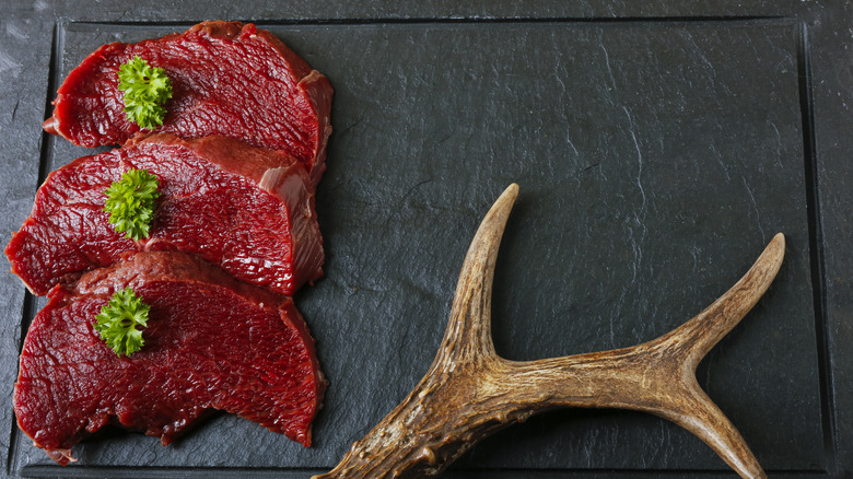 Venison steaks with parsley on slate next to antler