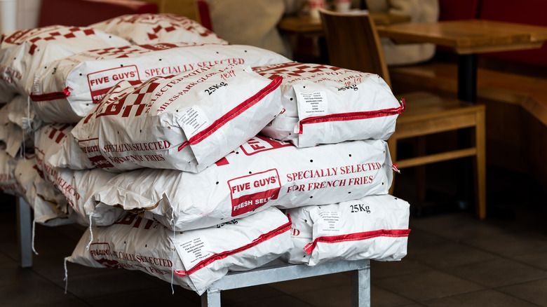 A stack of red and white bags of russet potatoes at Five Guys