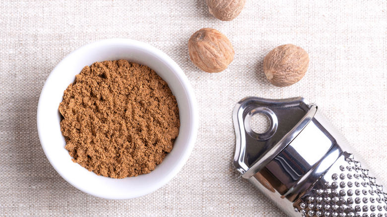 Ground nutmeg in a white bowl on linen fabric