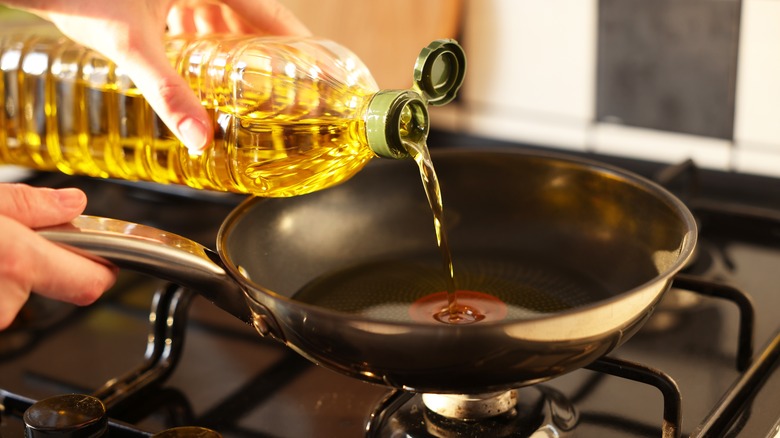 pouring oil into a pan on the stove