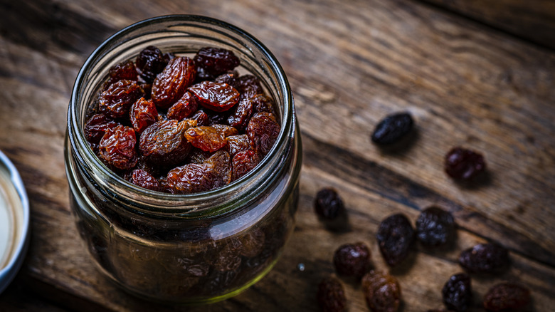 A jar of raisins on a wood background