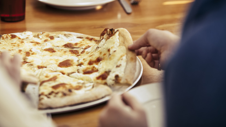 Hand taking slice of white pizza