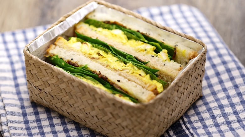 Coronation chicken sandwich in wicker container on checked napkin