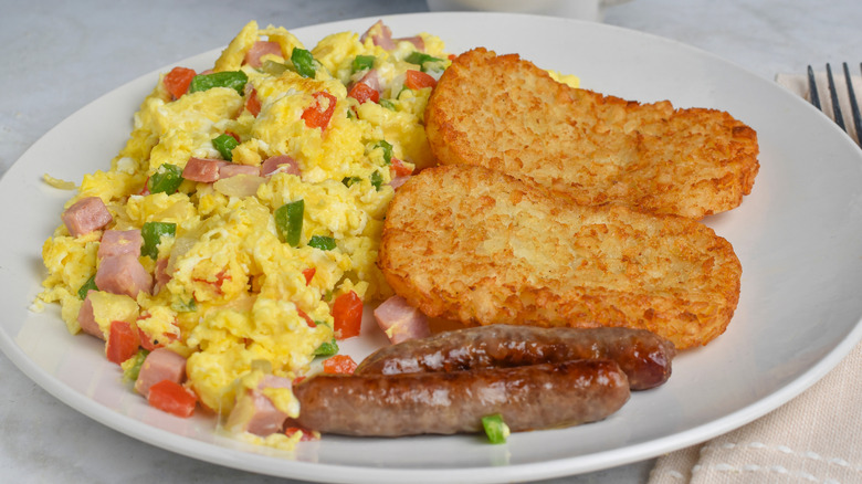 Scrambled eggs with peppers and ham, sausage links, and hash browns