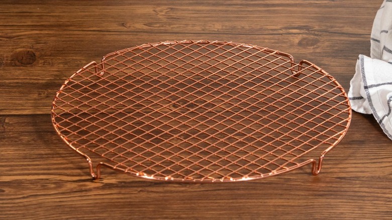 A circular cooling rack standing on a wooden surface.