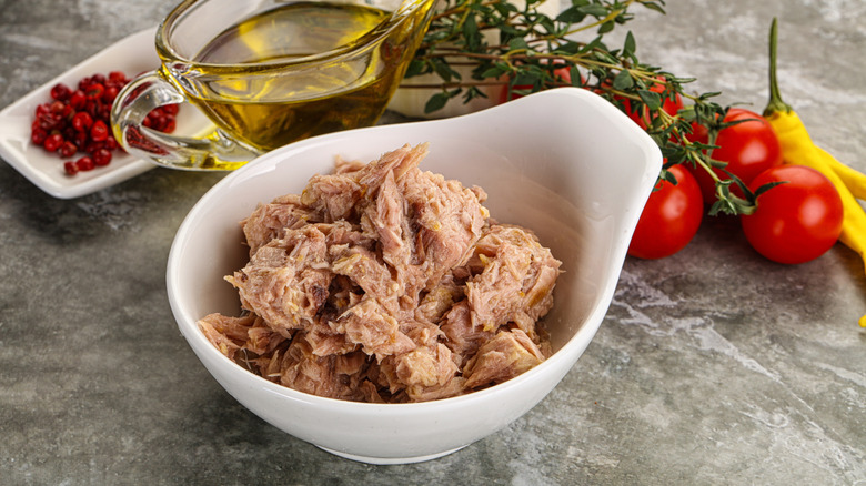 A white dish of canned tuna with fresh tomatoes, chilis, and olive oil in the background