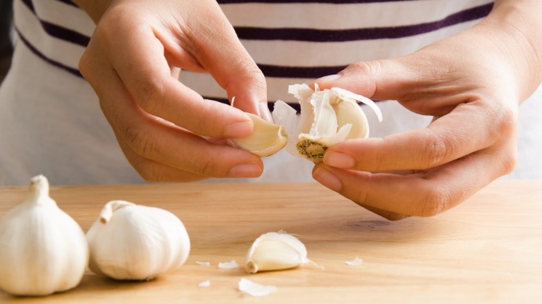 Close-up of person peeling garlic cloves.