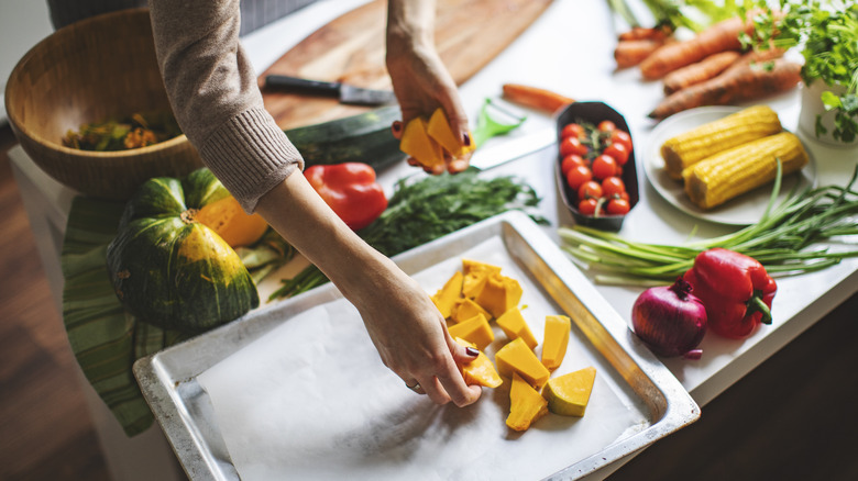 woman placing squash on a sheet pan tray