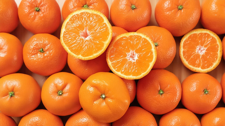 Rows of whole oranges with halved oranges on top