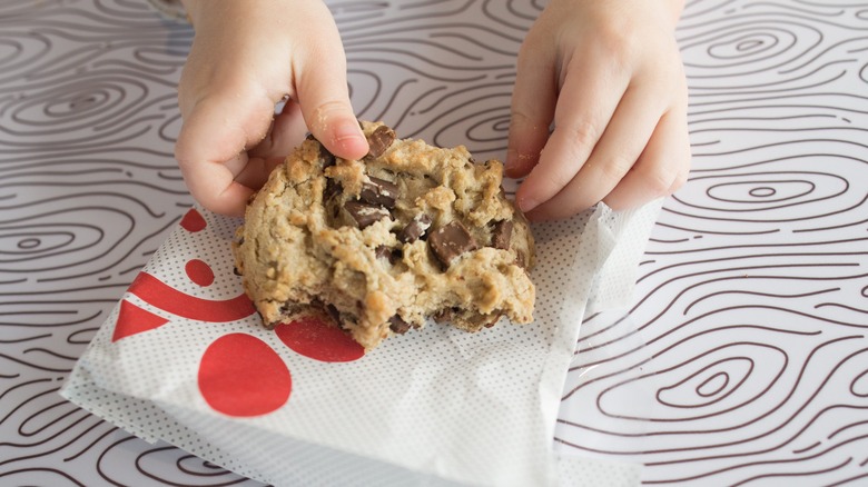 Hands holding a partially eaten Chick-fil-A Chocolate Chunk Cookie